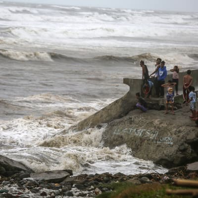 Filippiiniläisiä katsomassa myrskyävää merta.