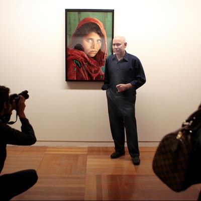 Valokuvaaja Steve McCurry kuvattuna maailmankuulun teoksensa 'Afghan Girl' (1985) vierellä restrospektiivinsä avajaisissa Santa Cruzissa, Teneriffalla, 13. maaliskuuta 2012. 