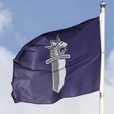 Liehuva lippu poliisin tunnuksella Tampereen poliisitalon edustalla.