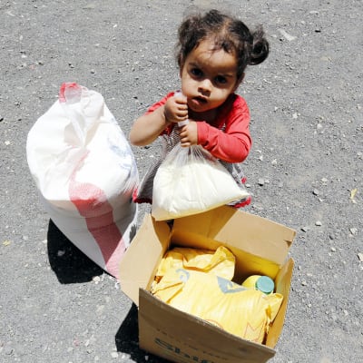 Jemeniläinen lapsi kuvattuna ruokaa sisältävän pahvilaatikon ääressä.