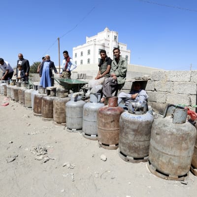 Jemeniläisiä miehiä jonottamassa tyhjien kaasutynnyrien kanssa Sanaassa.