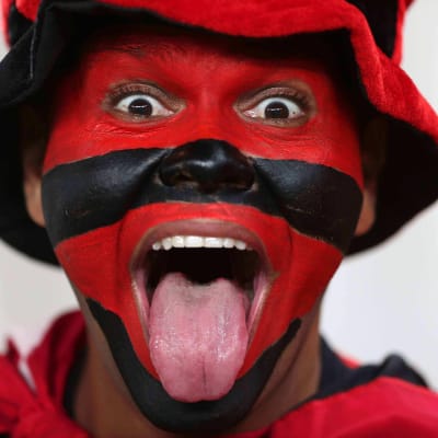 Poika jolla kasvot maalattu punaisin ja mustin raidoin näyttää kieltä