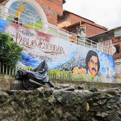 "Täällä hengitetään rauhaa" lukee seinämaalauksessa Pablo Escobarin nimeä kantavassa lähiössä. Muraalin yläpuolella on Escobarin äidin Meksikosta tuoma Kristus-lapsipyhimys.