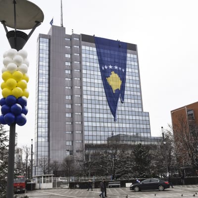 Isoa Kosovon lippua ripustetaan juhlistamaan maan kansallispäivää. Pylväissä on ilmapalloja.