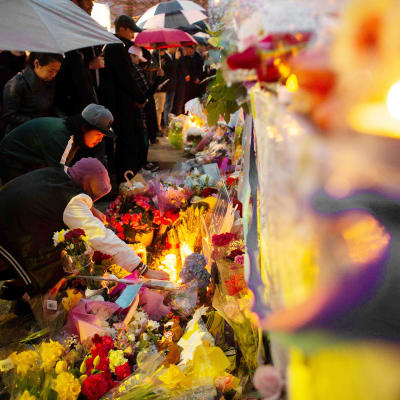 Ihmiset tuovat kukkia ja kynttilöitä surmapaikalle Torontossa.
