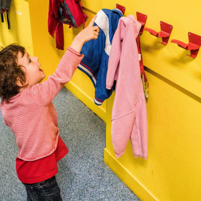 Lapsi päiväkodissa, osoittaa sormellaan  jotain ylhäällä seinällä olevaa asiaa.