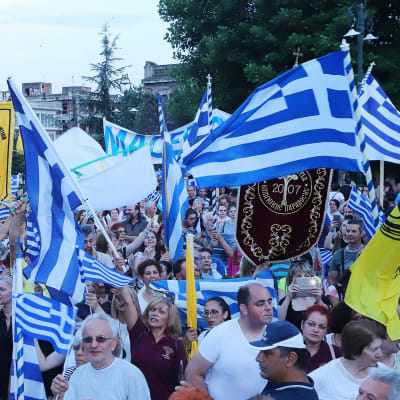Mielenosoittajat heiluttavat Kreikan lippuja.
