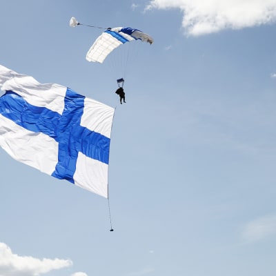 Laskuvarjohyppääjä tuo Suomen lipun avajaisissa Ilmavoimat 100 -vuotta juhlalentonäytöksessä Tikkakoskella.