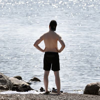 Mies seisoo rannassa.