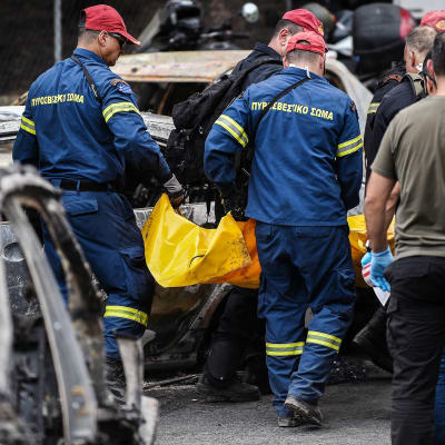 Kreikkalaiset pelastustyöntekijät kantavat ruumispussia Matin kaupungissa.