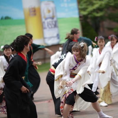 Flera personer iklädda antingen svarta eller vita dräkter. De dansar en japansk dans kallad yosakoi.