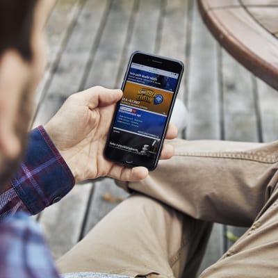 Mies selaa mobiilipelejä kännykästä.