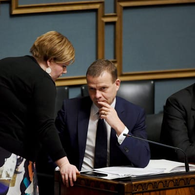 Valtiovarainministeri Petteri Orpoa ja perhe- ja peruspalveluministeri Annika Saarikko keskustelevat eduskunnan täysistunnossa.