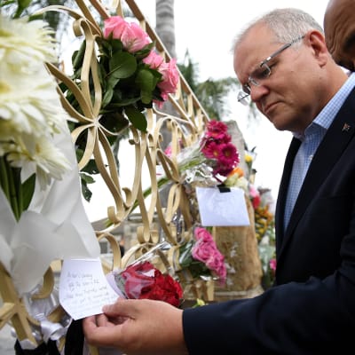 Australian pääministeri Scott Morrison tutkii terrori-iskun uhrien muistoksi tuotuja viestejä ja kukkia.