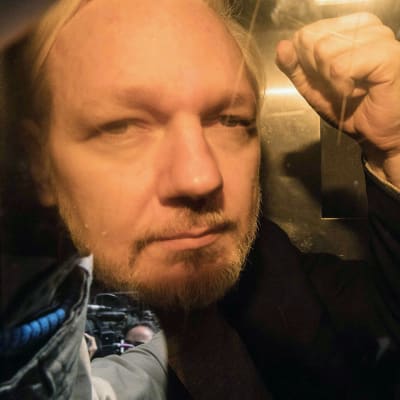 Julian Assange näyttää nyrkkiä kameroille.