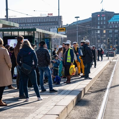 Ihmisiä jonottamassa ratikkaa Helsingin rautatieaseman luona.