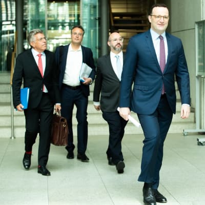 Terveysministeri Jens Spahn sekä asiantuntijat Martin Burg, Peer Briken ja Jörg Litwinschuh-Barthel kävelevät käytävällä.