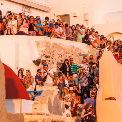 Turistit odottavat auringonlaskua Santorinilla.