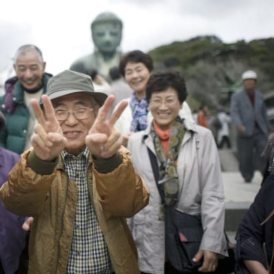 Vanhukset poseeravat Budha-patsaan edustalla Japanissa.