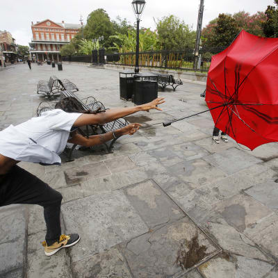 Sateenvarjo lentää miehen kädestä New Orleansissa.