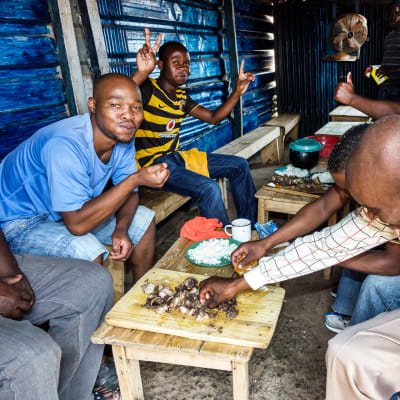 Miehet syövät lounasta  Etelä-Afrikassa.
