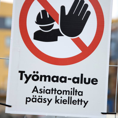 "Työmaa-alue"-kyltti rakennustyömaan aidassa. 