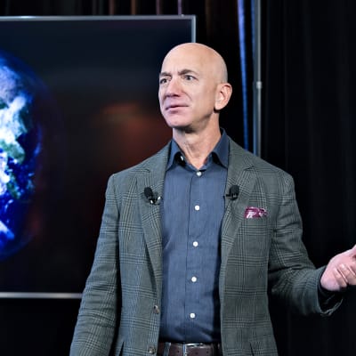 Jeff Bezos pitää puhettaan. Taustalla on maapallo kuvattuna avaruudesta.