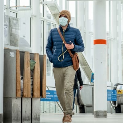 Mies kävelee Vuosaaren metroasemalla hengitysmaski kasvoillaan.