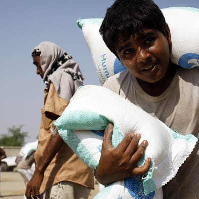Jemeniläispoika kantaa ruokasäkkejä Hajjahissa Jemenissä syyskuussa 2020.