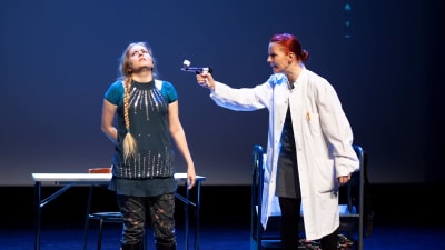 En person siktar på en annan person med pistol i en teaterpjäs.