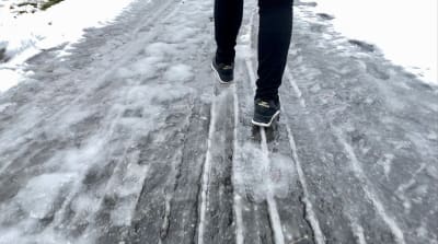 En person går med skor på en isig väg.