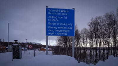 En blå skylt där det står "Schengen border, restricted area" vid den rysknorska gränsen. Snöigt landskap.
