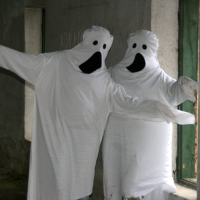 Två människor utklädda till spöken (med hjälp av vita lakan).