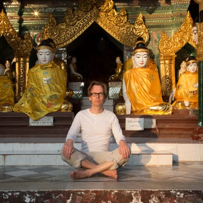 Kaj Arnö sitter framför buddhastatyer