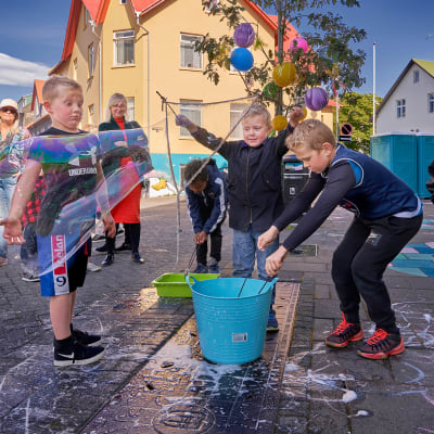Islantilaiset lapset tekevät saippuakuplia.