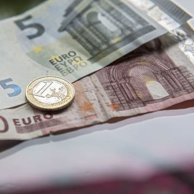 Seteleitä ja euron kolikko pöydällä.