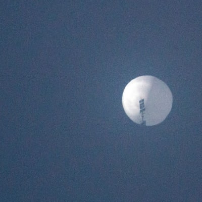 En lite suddig bild på en rund, vit ballong mot mörkblå himmel.