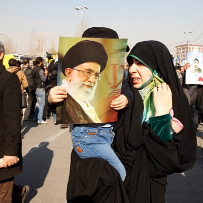 Iranilaisnainen lapsineen hallintoa tukevalla marssilla Teheranissa 5. tammikuuta 2018. Naisen kädessä Iranin hengellisen johtajan Ali Khamenein kuva.