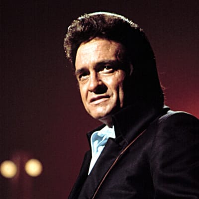 Johnny Cash har en akustisk gitarr som hänger på hans rygg.