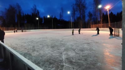 Barn skrinnar och spelar med klubbor på Isnäs sportplan.