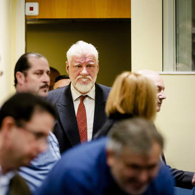 Bosnian kroaattijoukkoja 1990-luvulla komentanut Slobodan Praljak saapui oikeuteen Haagissa Hollannissa 29.11.2017. Harmaatukkainen Praljak kuvassa ihmisjoukon keskellä.