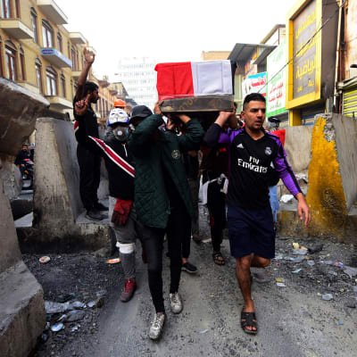 Irakilaiset kantavat turvallisuusjoukkojen tapaaman protestoijan arkkua Bagdadissa.