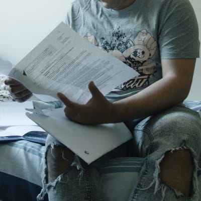 Kuvassa nuori mies tutkii paperia. 