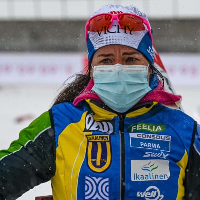 Krista Pärmäkoski står i målområdet iklädd munskydd och gulblå jacka med skidglasögon på huvudet.