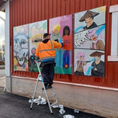 Oriveden kaupungin työntekijä puhdistaa rautatieaseman seinässä olevaa töhrittyä nuorten tekemää taideteosta.  