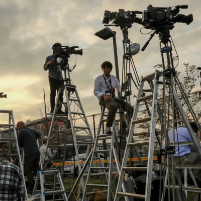 Median kuvaajat seisovat korkeilla A-tikkailla videokameroidensa kanssa.