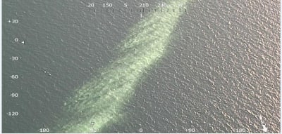 Ett flygfoto av ett långt gulvitt utsläpp av kalciumkarbonat i havet.