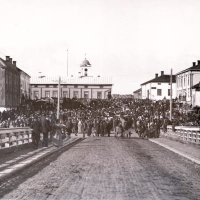 En stor folkmassa är samlad på ett torg i slutet av 1800-talet.