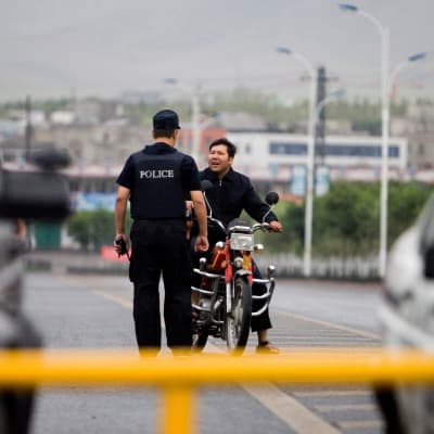 En polis stoppar en man av uiguriskt ursprung i Xinjiang. 