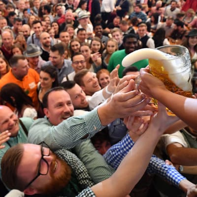 Folk sträcker sig efter ett ölstop på Oktoberfest.